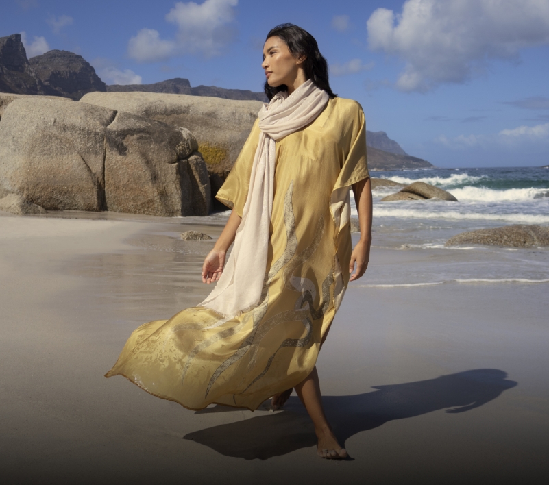 Model on beach near boulders